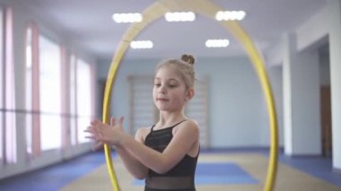 Talented young girl performing gymnastic exercises (palm spin of hula hoop)