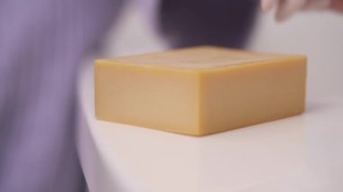 A demonstration close-up video of woman's hand putting a lavender inflorescences on the piece of handmade soap