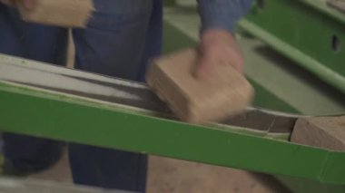 Yakın plan üretilmiş ahşap briketler. Bir işçi, briketleri sırasından ayırıyor..