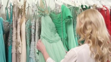 Güzel dalgalı saçlı, yeşil gece elbisesinin tadını çıkaran sarışın bir kadının dönüşümlü kamera görüntüsü.