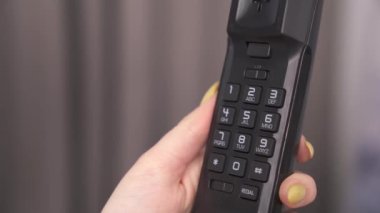 Telefonun düğmelerini tutan ve telefon numarası dağıtan bir kadın eli.