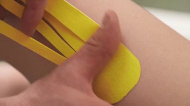 Fizyoterapist kadın hastaların dizlerine parlak bir rehabilitasyon bandı yapıştırıyor. Alternatif kinesio bant terapisi, sağlık hizmeti