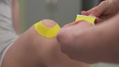Fizyoterapist kadın hastaların dizlerine Kinesio bandı yapıştırıyor. Diz eklemi tedavisi. Spor ve rehabilitasyon