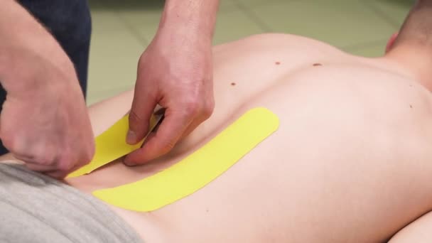 Vídeo Demostración Terapeuta Grabando Cinta Kinesio Espalda Paciente Masculino Tratamiento — Vídeos de Stock