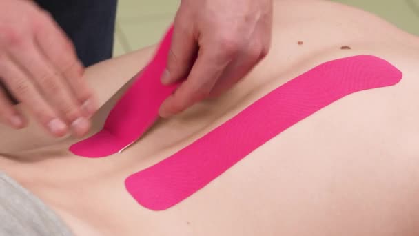 Therapeut Repareert Medische Tape Strepen Een Patiënt Terug Mannelijke Patiënt — Stockvideo