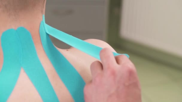 환자의 어깨에 테이프를 부착하는 치료사 — 비디오