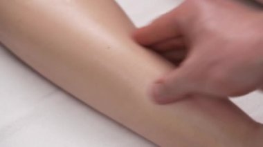 Isınmak için baldır kasına masaj yapan bir fizyoterapist. Fizyoterapi ve rehabilitasyon