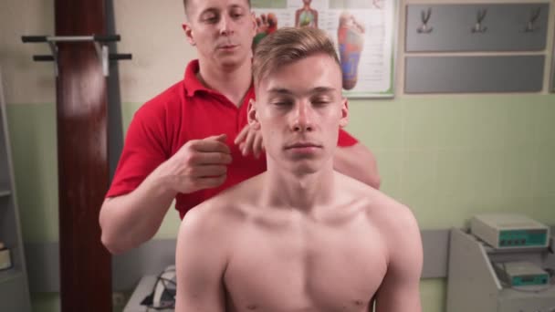 若いスポーツマンの患者に力を伸ばす手技療法士の正面図 子宮頸椎疼痛緩和療法 — ストック動画