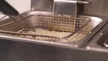 Patates kızartmaları kaynar yağdan kaldırılır. Daldırmak inanılmaz lezzetli görünüyor. Fast food restoranı.