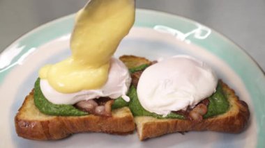Benedict yumurtasına Hollandaise sosu döken bir şef. Amerikan kahvaltısı ya da brunch yemeği. Haute cuisine konsepti