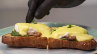 Taze pişmiş klasik yumurta Benedict 'i dekore eden bir şef. Amerikan kahvaltısı ya da brunch yemeği. Gıda tasarımı konsepti