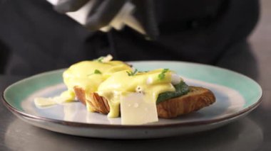 Benedict yumurtalarına zeytin yağı döken bir şef. Amerikan kahvaltısı ya da brunch yemeği. Gıda tasarımı konsepti