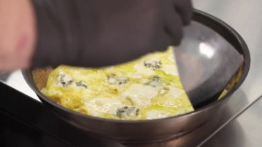 Pişmiş yumurtalı omleti sıcak tavadan çıkaran bir şefin gösteri videosu..