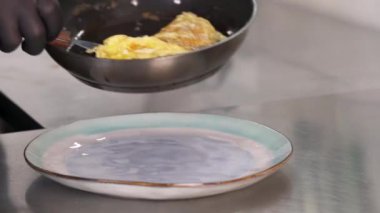 Tavadan yumurta omleti yapan bir şefin yakın plan görüntüsü..