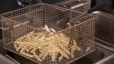Kızartma makinesine dilimlenmiş çiğ patates koyarken çekilmiş yakın plan bir video. Patates kızartması.