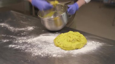 Usta bir fırıncı karıştırma kabından ekmek hamurunu alır ve daha fazla yoğurmak için masaya koyar.