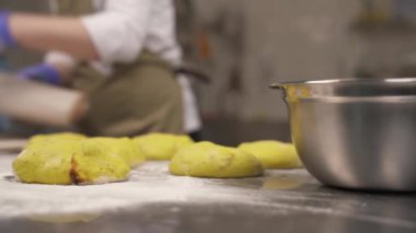 Ön planda şekillendirilmiş ekmek somunları. Profesyonel bir fırıncı kumaş parçasını koruma tepsisine koyuyor..