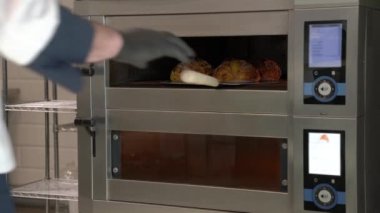 Fırıncının ellerinin kabuğunu tutarken ve fırından taze pişmiş ekmek çıkarırken yan görüntüsü. Fırında ekmek pişiriyorum. Yemek pişirme konsepti