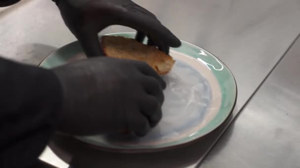 大厨们手拿着黑色手套的特写镜头 将半边切好的烤羊角面包放在盘子里 — 图库视频影像