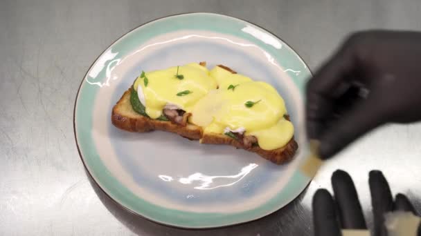 薄切りのパルメザンチーズで焼きたての古典的な卵のベネディクトを飾るシェフ — ストック動画