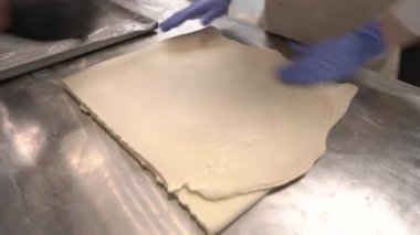 Uzman bir şefin hamur kalıplarını kaplayıp pişirme tepsisine koyduğu yakın plan bir gösteri videosu. Kruvasan ve pastane ürünleri yapıyorum.