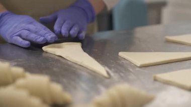 Profesyonel bir fırıncı hamur yoğurur ve kruvasanları pastanedeki fırın tepsisine koyar..