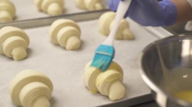 Profesyonel bir şef kruvasana çiğ yumurta sarısı döküyor. Malzemeler hazırlanıyor. Fırın kavramı