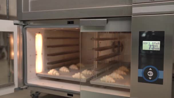 烘烤前的新月卷 工人们正在把一个装有羊角面包的盘子放进烤箱 羊角面包的防伪 面包店 糕点店 — 图库视频影像