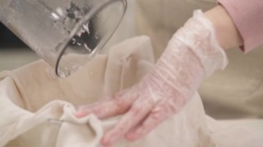 Muslin bezini hindistancevizi karışımıyla saran ve sütü sıkan bir kadın eli. Muslin 'in içinde posasını bırakıyor.