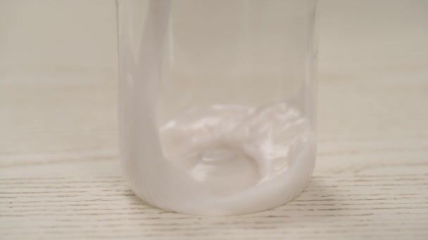ガラス瓶に牛乳を入れる 女性の手は牛乳でジャグを持ち ボトルに注ぎ キャップでボトルを閉じます ココナッツミルク作り — ストック動画