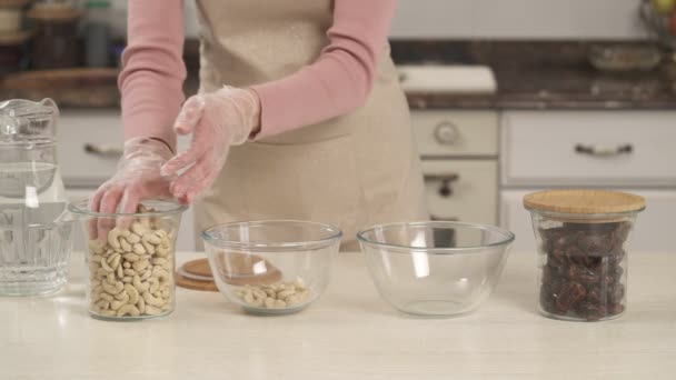 Förbereder Ingredienser Kvinna Fylla Glas Skålar Med Cashewnötter Och Torkade — Stockvideo