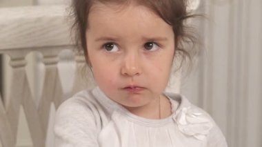 Lezzetsiz yemek çiğneyen sevimli küçük bir kızın yakın plan videosu. Gerçek duygular. Komik çocuk konsepti