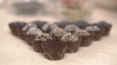 Karton kurabiye bardağında yuvarlak çikolatalı şekeri tutan ve geri kalan şekerlere yerleştiren bir kadının yakın çekim videosu.