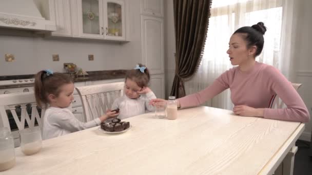 Młoda Matka Jej Bliźniaczki Jedzą Domowe Słodycze Rozmawiają Kuchni Szczęśliwa — Wideo stockowe