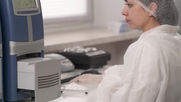 一个专业的实验室技术人员用装有生物样品的微型管子来装载微板读取器 生物化学分析用微晶片读取器 — 图库视频影像