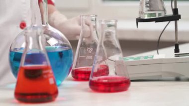 Laboratuvar teknisyeninin profesyonel tıbbi ekipman kullanarak biyolojik örnekler üzerinde yaptığı araştırma. Bilim adamı kimyasal reaktörlü bir matara alıyor..