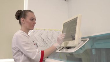 Profesyonel otomatikleştirilmiş analiz cihazı kullanarak kan testi yapan genç bir kadın tıp teknisyeninin yakın çekimi. Profesyonel laboratuvar tıbbi ekipmanları. Sağlık hizmetleri kavramı.