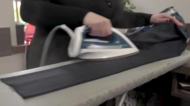 Kadın ütü masasında siyah erkek klasik pantolonunu ütülüyor. Yakın çekim gösteri videosu