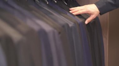 Butikteki erkek klasik ceketlerinin yakın plan çekimleri. Kıyafet seçen müşteri. Lüks moda mağazası kavramı