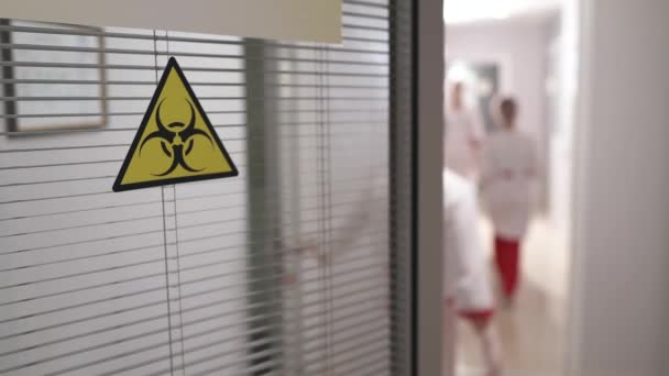 在实验室工作的人实验室入口门上生物威胁警报的生物危害标志 — 图库视频影像