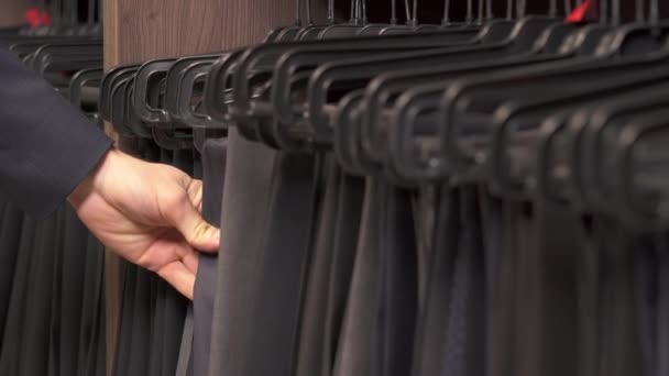 ブティックでクラシックスタイルの男性パンツ 顧客が服を選ぶ ファッション閉店のコンセプト — ストック動画
