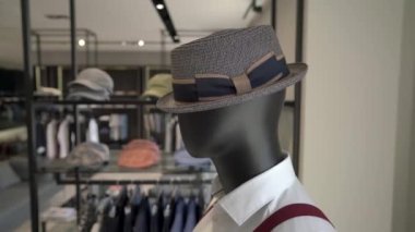 Pahalı erkek giyim mağazasında şık bir şapka takan erkek mankenlerin yakın çekimi. Moda endüstrisi