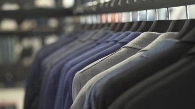 Klasik yelek giyen bir işadamı dükkandaki takım elbiseli adamlara karşı. Arka plan bulanık. Ticari moda mağazası kavramı