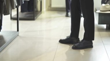 Şık erkek takım elbiseli yakışıklı bir adamın butikte kıyafet seçerken en alttaki fotoğrafı. Ticari moda mağazası kavramı