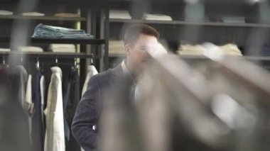 Yakışıklı müşteri, lüks bir erkek giyim mağazasında telefonla konuşuyor..