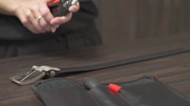 Özel aletlerle siyah deri kemeri kısaltan bir bayan tezgahtar. Alışveriş ve satış konsepti.