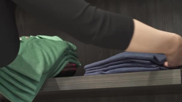 Een Close Van Winkelassistent Die Kleurrijke Stijlvolle Shirts Een Plank — Stockvideo