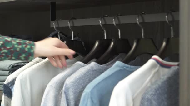 一个由女性售货员组成的特写镜头 用不同的男性T恤衫在金属货架上手工缝制衣架 特写示范 奢侈品商务时装店的概念 — 图库视频影像