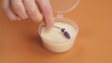 Doğal krem ile dolu şeffaf plastik bir konteynere lavanta kabı koyup kapatıyorlar. Zanaat kozmetikleri