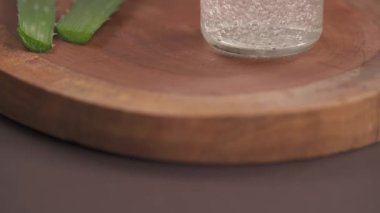 Aloe vera jeliyle dolu küçük bir cam şişenin altı. Arka planda bulanık aloe vera bitkisi yaprakları. Doğal cilt bakımı. Seçici odak